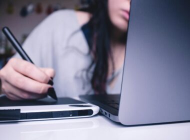 woman using drawing pad while sitting in front of laptop